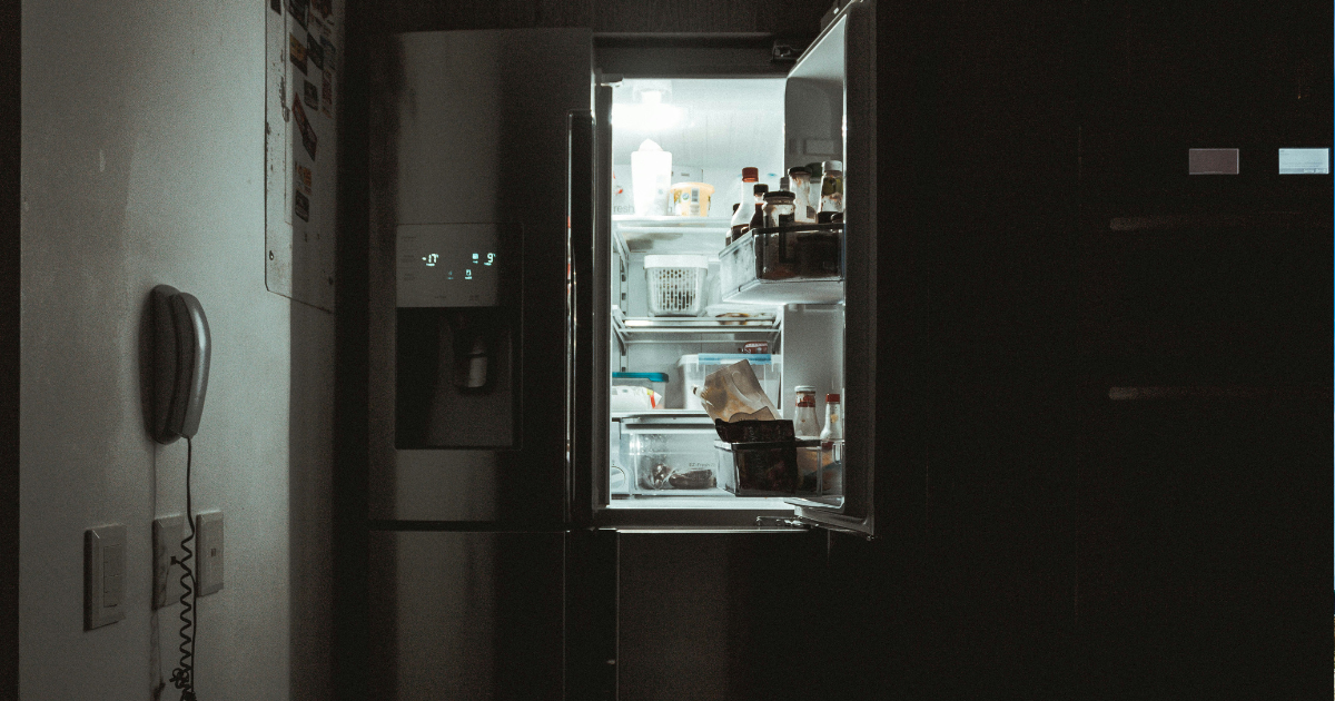 A portable solar generator connected to a kitchen refrigerator during a power outage, featuring solar panels visible through a window and a 24/7 digital overlay.