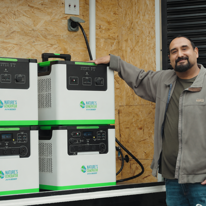 Scene - A man in a gray jacket stands next to a stack of white and green portable power stations branded Nature's Generation, set against an OSB wood wall background.